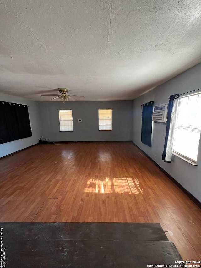 unfurnished room with a textured ceiling, hardwood / wood-style flooring, and plenty of natural light