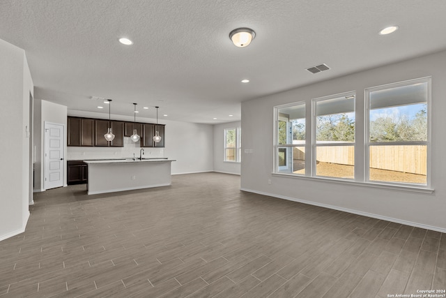 unfurnished living room with sink, dark wood-type flooring, and a textured ceiling