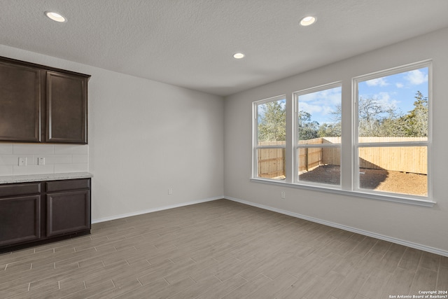 unfurnished dining area featuring light hardwood / wood-style flooring, a textured ceiling, and a healthy amount of sunlight