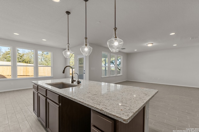 kitchen featuring dark brown cabinets, sink, pendant lighting, and a center island with sink