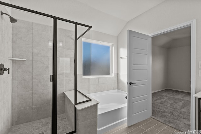 bathroom with shower with separate bathtub, hardwood / wood-style flooring, and vaulted ceiling