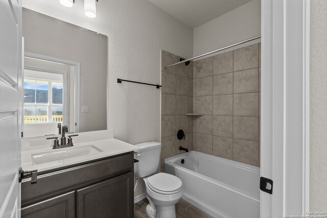 full bathroom with toilet, tiled shower / bath, hardwood / wood-style floors, and vanity