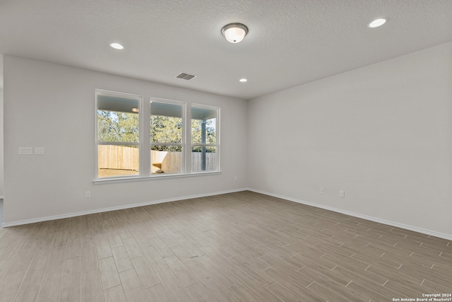 unfurnished room with light hardwood / wood-style flooring and a textured ceiling