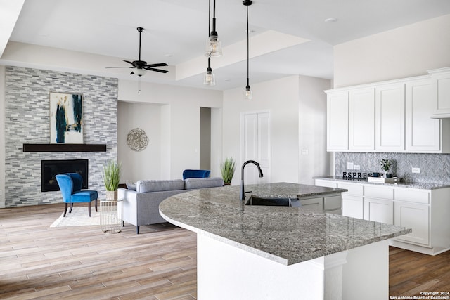 kitchen featuring pendant lighting, white cabinetry, sink, and a kitchen island with sink