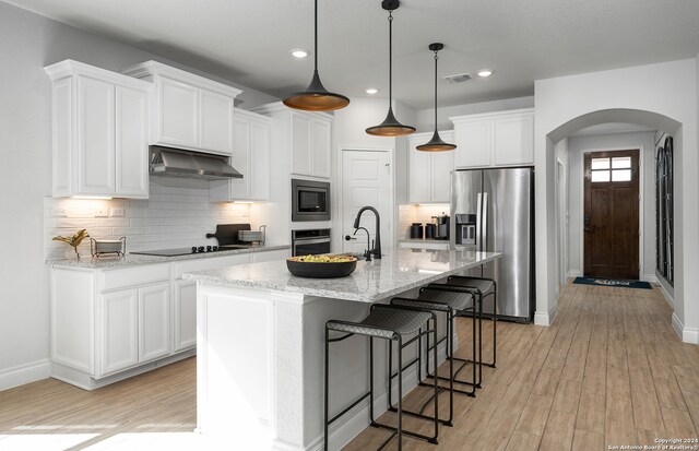 kitchen with extractor fan, light hardwood / wood-style flooring, an island with sink, white cabinetry, and appliances with stainless steel finishes