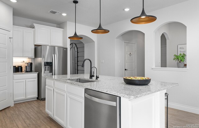 kitchen featuring sink, an island with sink, decorative light fixtures, and stainless steel appliances