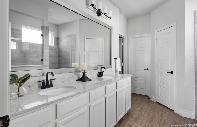 bathroom with vanity, hardwood / wood-style floors, and tiled shower