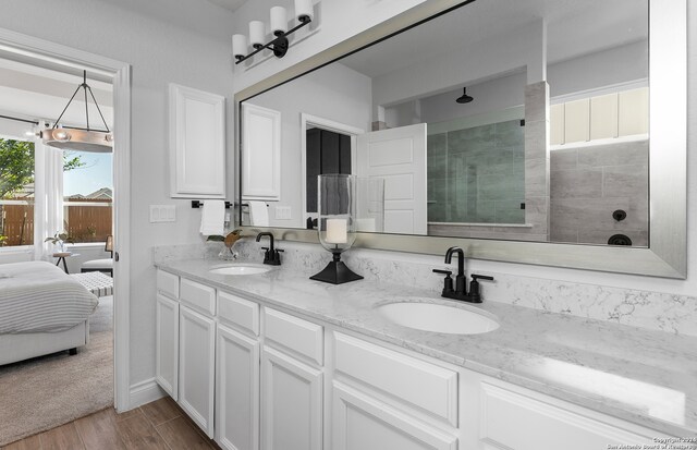 bathroom with vanity, hardwood / wood-style floors, a tile shower, and an inviting chandelier