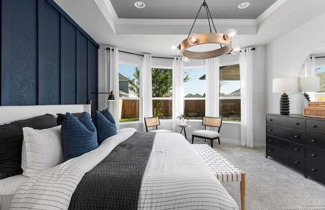 carpeted bedroom featuring a notable chandelier, ornamental molding, and a tray ceiling