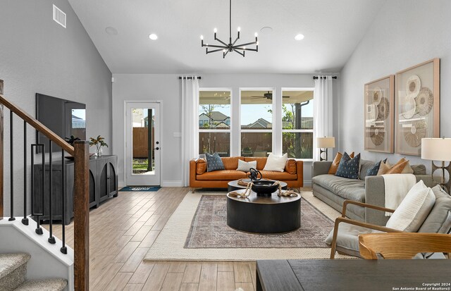 living room with light hardwood / wood-style flooring, a chandelier, and vaulted ceiling