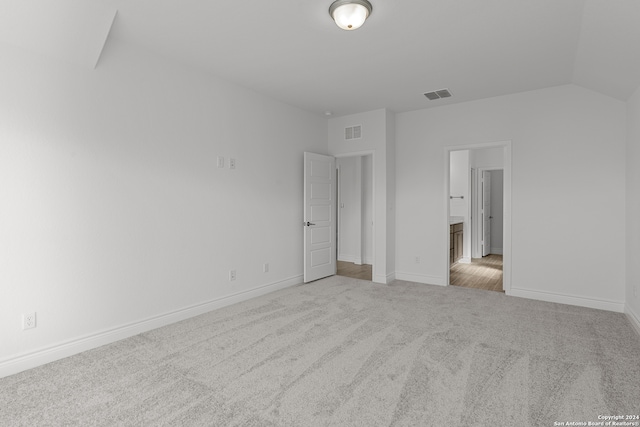 unfurnished bedroom featuring light carpet and vaulted ceiling