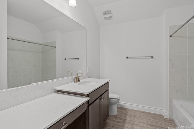 full bathroom featuring hardwood / wood-style flooring, toilet, tiled shower / bath, vaulted ceiling, and vanity