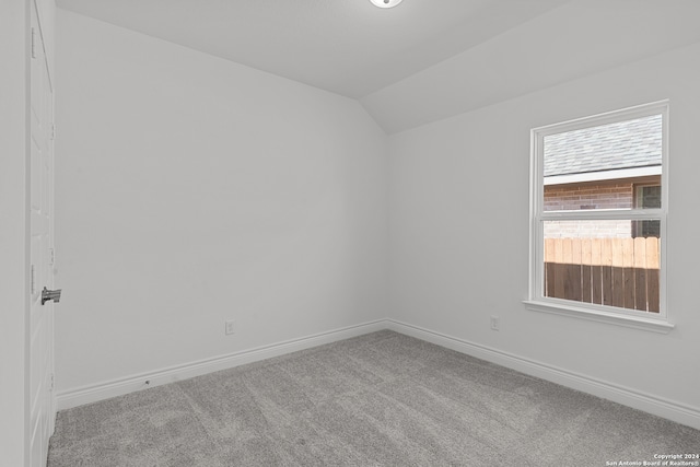 carpeted spare room featuring lofted ceiling