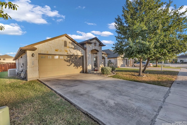 view of front of home featuring a front yard, central AC, and a garage