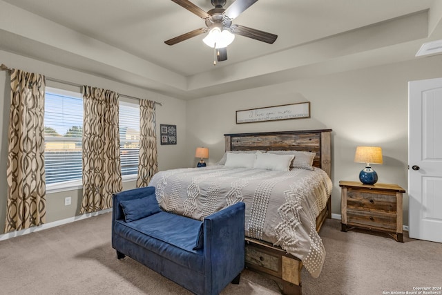 carpeted bedroom featuring a raised ceiling and ceiling fan