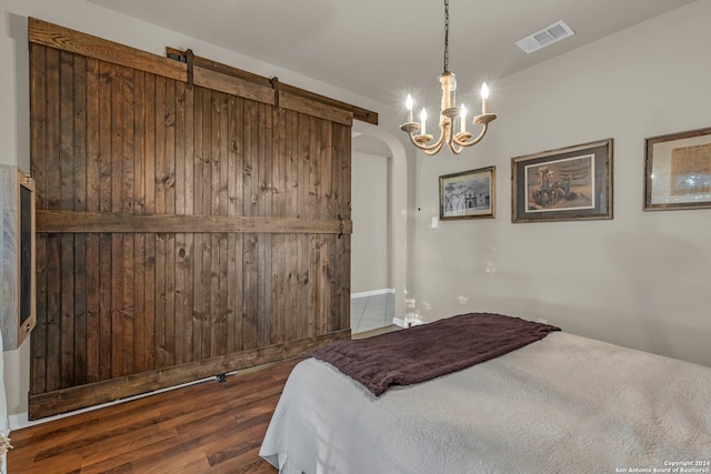 bedroom featuring a notable chandelier, a barn door, and dark hardwood / wood-style flooring