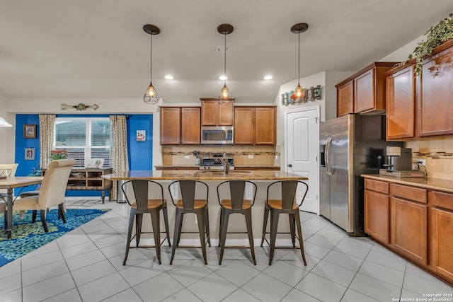 kitchen featuring tasteful backsplash, sink, pendant lighting, and an island with sink