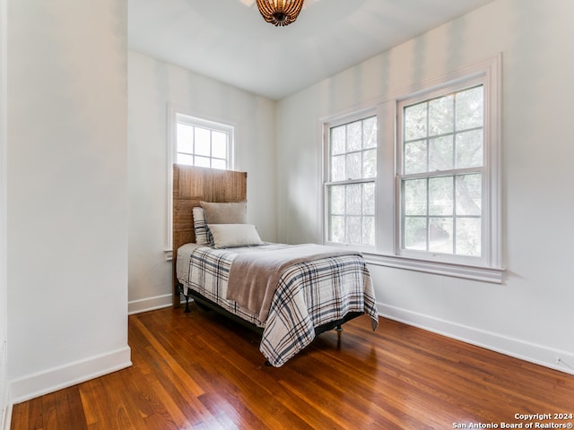 bedroom with multiple windows and dark wood-type flooring