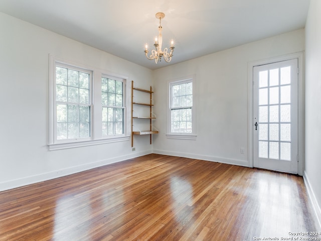 empty room with a notable chandelier and hardwood / wood-style floors