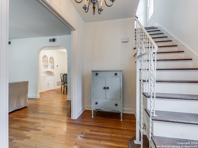 stairs featuring hardwood / wood-style floors and an inviting chandelier