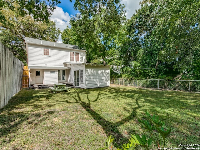 rear view of house featuring a wooden deck and a yard