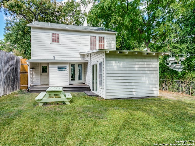 rear view of house with french doors and a lawn