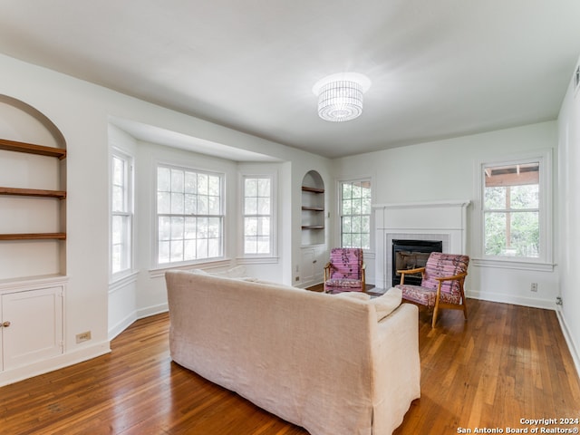 living room with a chandelier, wood-type flooring, and built in features