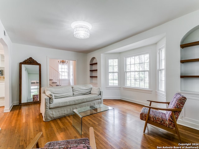 bedroom with a notable chandelier, multiple windows, and light wood-type flooring