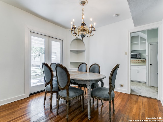 dining space featuring a chandelier, french doors, built in features, and dark hardwood / wood-style flooring