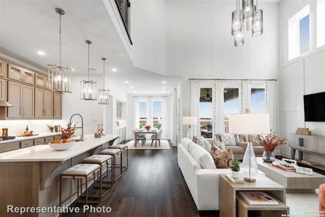 living room with a towering ceiling, dark wood-type flooring, and sink