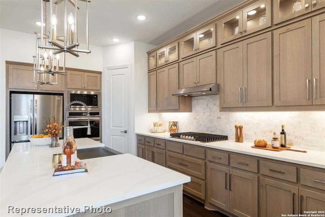 kitchen with dark wood-type flooring, stainless steel appliances, backsplash, a chandelier, and pendant lighting