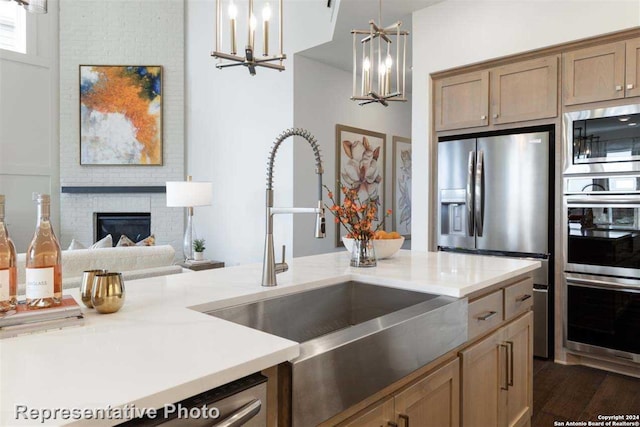 kitchen with appliances with stainless steel finishes, dark hardwood / wood-style flooring, sink, a fireplace, and hanging light fixtures