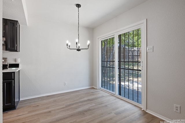 unfurnished dining area featuring light hardwood / wood-style flooring and an inviting chandelier