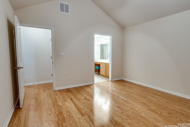 spare room featuring built in desk, light hardwood / wood-style floors, and lofted ceiling