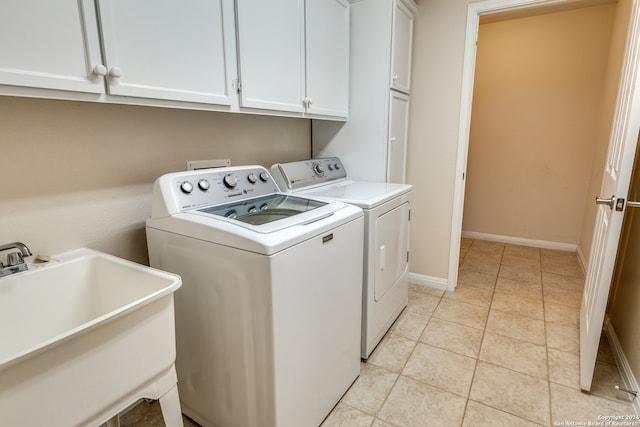 clothes washing area featuring cabinets, sink, washer and clothes dryer, and light tile patterned floors