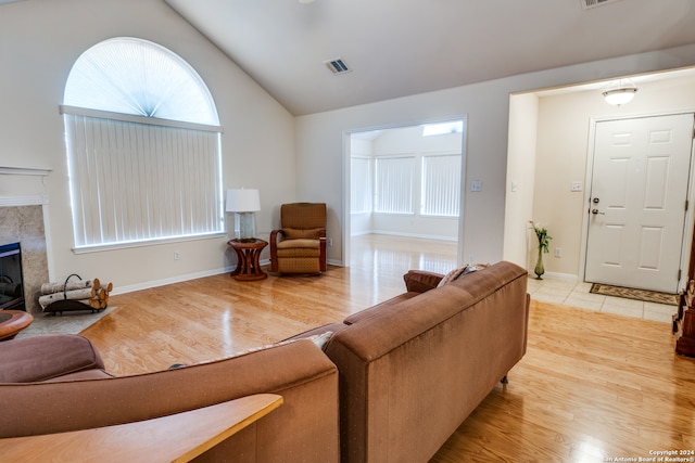 living room with vaulted ceiling, light wood-type flooring, and a fireplace