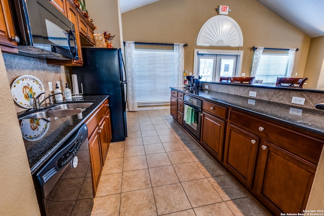 kitchen with black appliances, sink, lofted ceiling, dark stone counters, and light tile patterned floors