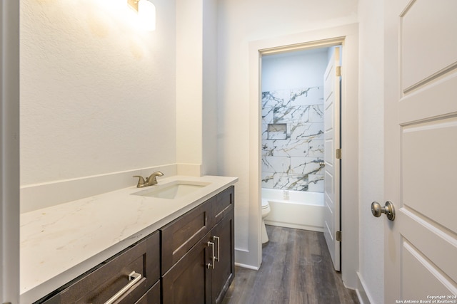 full bathroom featuring hardwood / wood-style floors, vanity, toilet, and tiled shower / bath