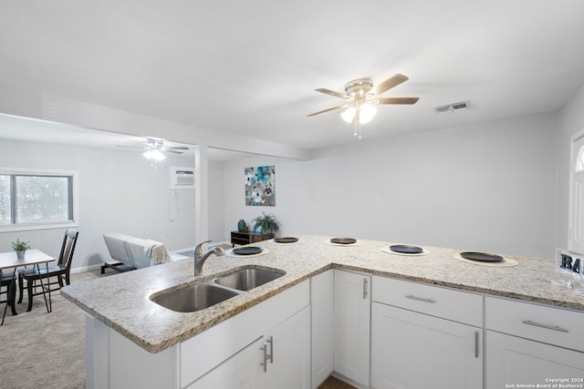 kitchen with light carpet, white cabinets, a wall mounted AC, light stone counters, and sink