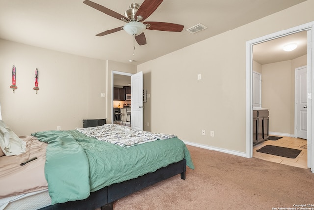 carpeted bedroom with ensuite bathroom and ceiling fan