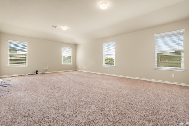 carpeted empty room with lofted ceiling