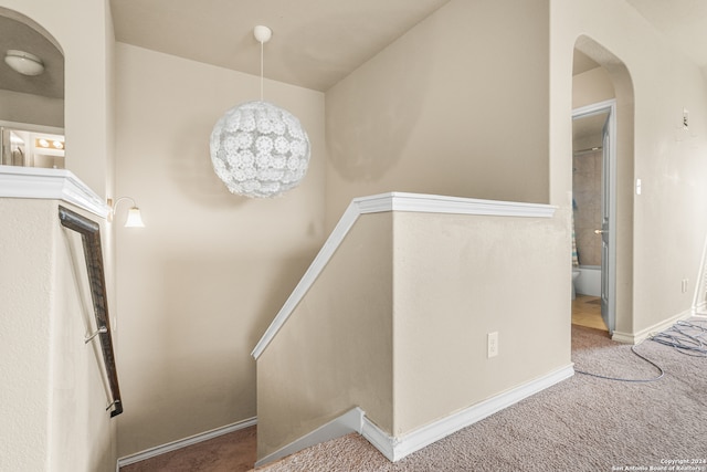 stairs with a notable chandelier and carpet flooring