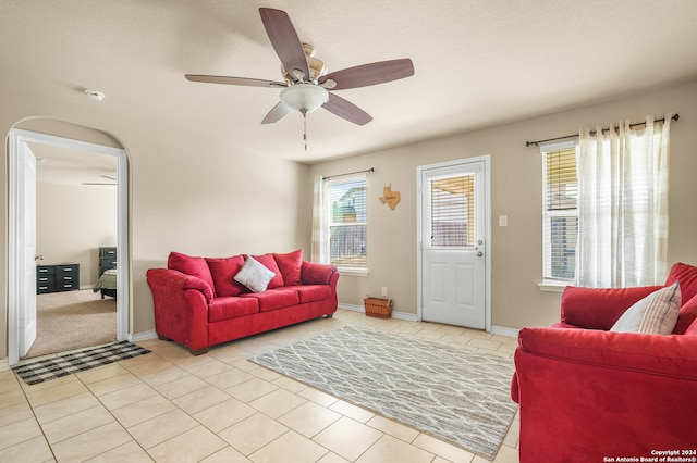 living room featuring a textured ceiling, light tile patterned floors, and ceiling fan