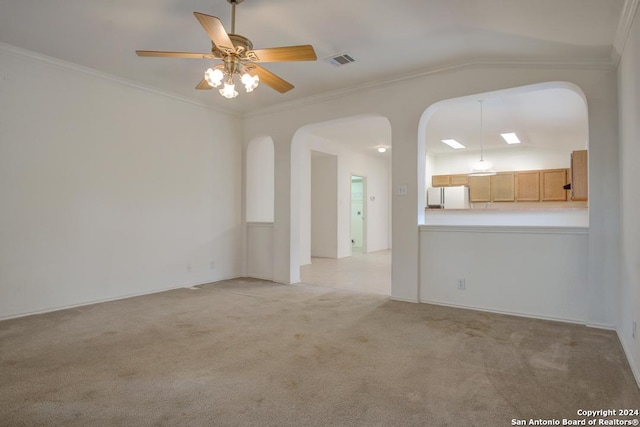 spare room with ceiling fan, ornamental molding, vaulted ceiling, and light colored carpet