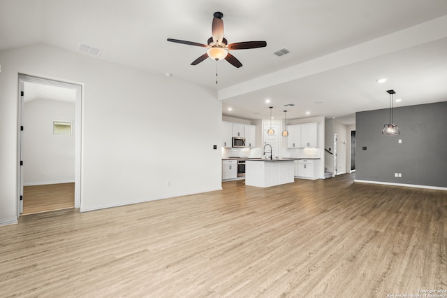 unfurnished living room with light hardwood / wood-style floors, sink, and ceiling fan