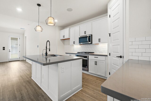 kitchen featuring hanging light fixtures, hardwood / wood-style floors, sink, white cabinets, and appliances with stainless steel finishes