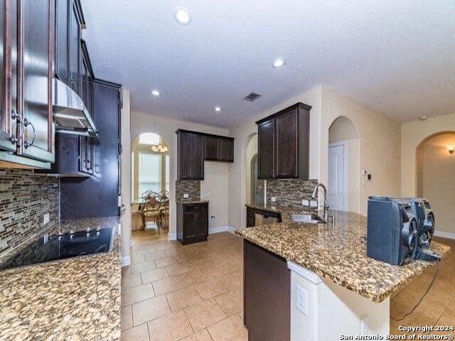 kitchen featuring black electric stovetop, stone countertops, tasteful backsplash, and sink