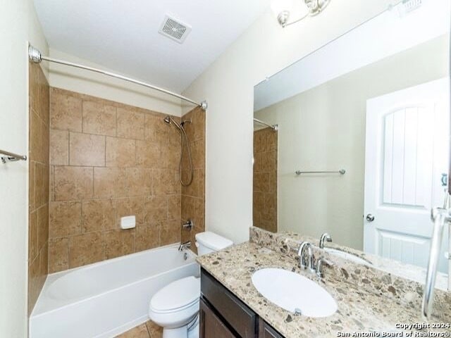 full bathroom featuring toilet, tiled shower / bath combo, vanity, and tile patterned floors