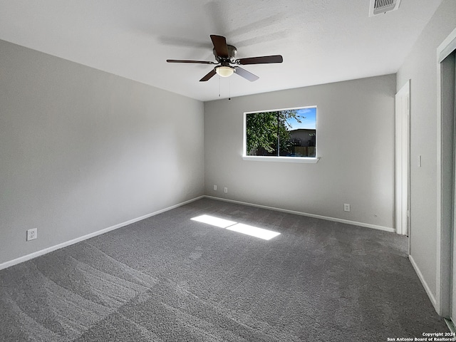 unfurnished room with ceiling fan and dark colored carpet