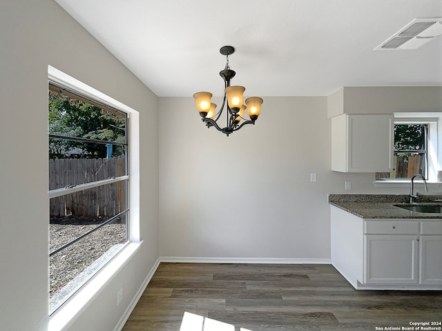 unfurnished dining area with a healthy amount of sunlight, sink, a chandelier, and dark hardwood / wood-style floors